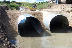 Photo of 2 large culverts being installed in a ditch.