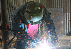 Photo of man welding with safety mask and sparks